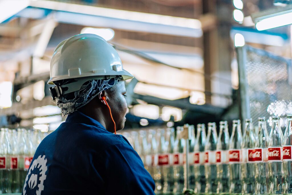 Trabajadora con casco de seguridad en una línea de embotellado de Coca-Cola